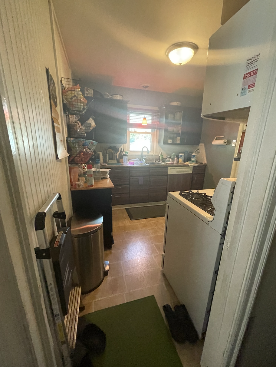 Over-crowded galley kitchen in dark and dingy finishes cluttered with household items Over-crowded galley kitchen in dark and dingy finishes cluttered with household items