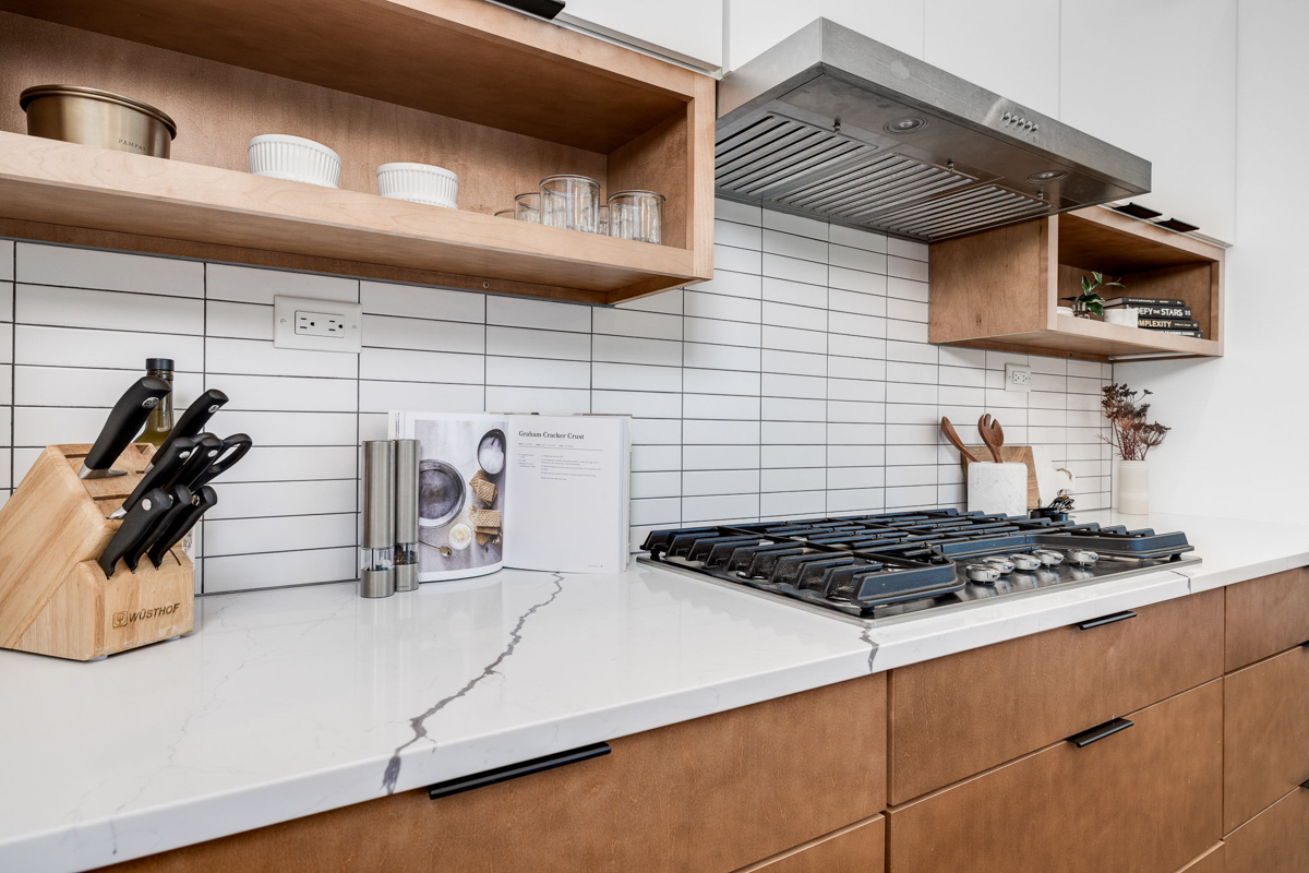 Mid-century modern kitchen design with white slab cabinets along one wall with warm wood base cabinets and accents plus a warm wood kitchen island and white quartz countertops Mid-century modern kitchen design with white slab cabinets along one wall with warm wood base cabinets and accents plus a warm wood kitchen island and white quartz countertops