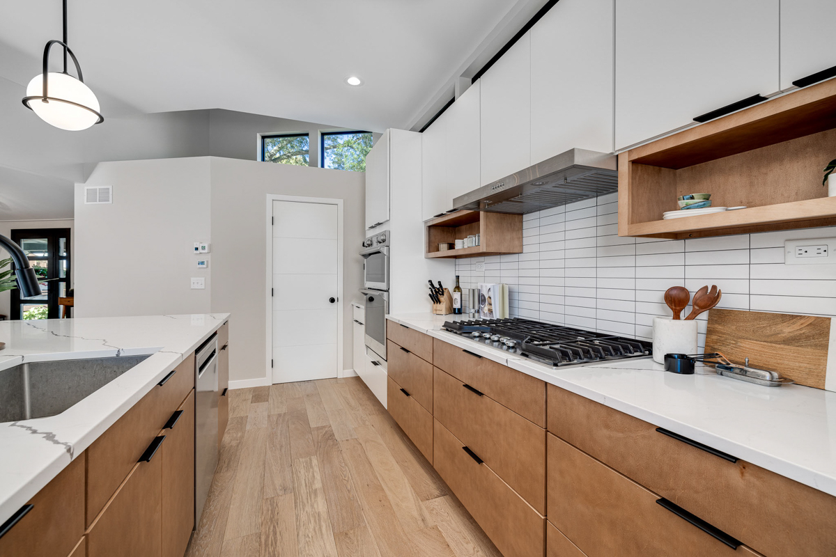 Mid-century modern kitchen design with white slab cabinets along one wall with warm wood base cabinets and accents plus a warm wood kitchen island and white quartz countertops Mid-century modern kitchen design with white slab cabinets along one wall with warm wood base cabinets and accents plus a warm wood kitchen island and white quartz countertops