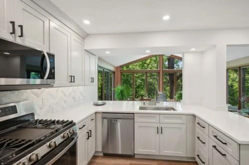 Canyon Oyster kitchen cabinets U-shaped light gray shaker kitchen design with peninsula and black hardware