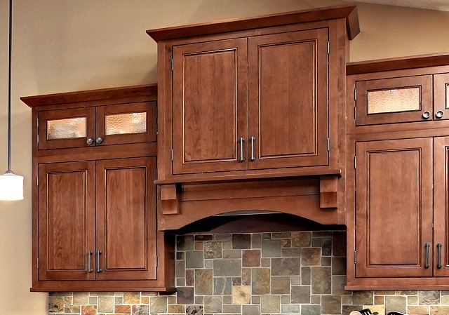 cherry glass-door cabinets bordering custom wood range hood. Hood projects forward for visual interest cherry glass-door cabinets bordering custom wood range hood. Hood projects forward for visual interest