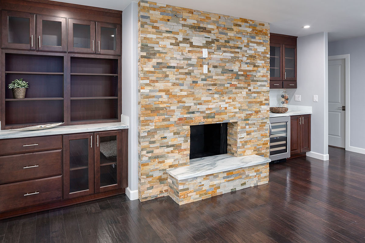fireplace surround created by bookshelf walls of cherry cabinets in Bayport raised panel style with glass doors and slab-front drawers and builtin beverage cooler fireplace surround created by bookshelf walls of cherry cabinets in Bayport raised panel style with glass doors and slab-front drawers and builtin beverage cooler