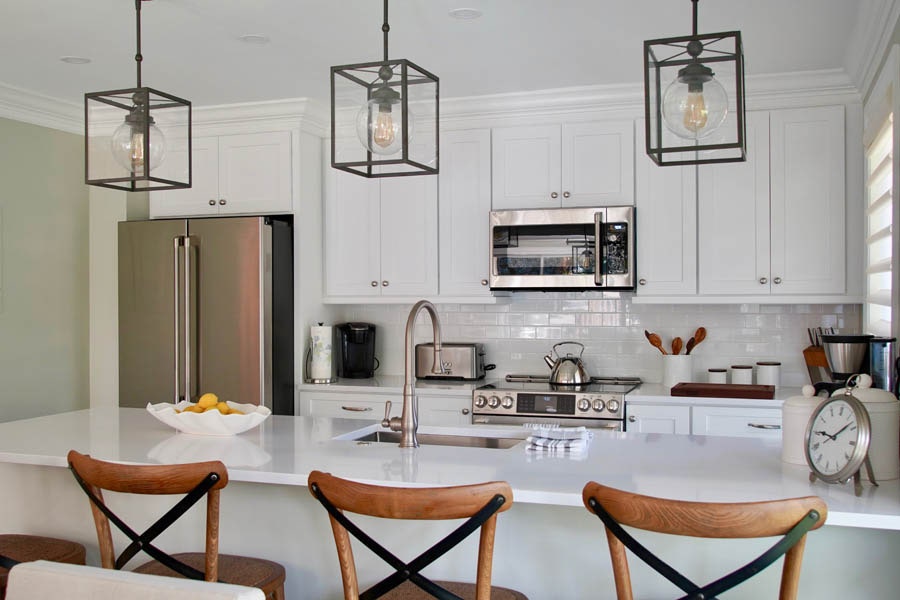 Kitchen with white shaker cabinets, black metal fixtures, stainless appliances and wood chairs on peninsula Kitchen with white shaker cabinets, black metal fixtures, stainless appliances and wood chairs on peninsula