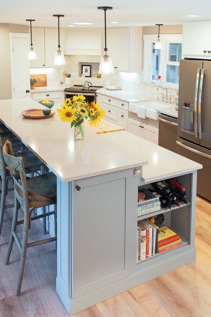 White kitchen with large two-tier blue island, stainless appliances and corner range White kitchen with large two-tier blue island, stainless appliances and corner range