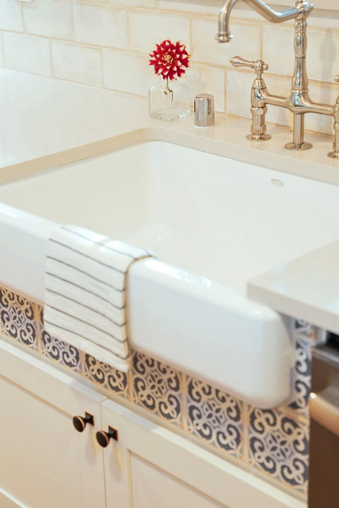 White apron sink with blue tile detail below the front skirt White apron sink with blue tile detail below the front skirt