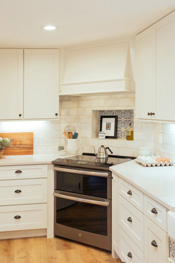Stainless steel range in the corner of a kitchen with white cabinets and range hood Stainless steel range in the corner of a kitchen with white cabinets and range hood