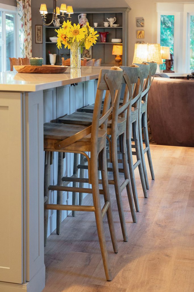 Four chairs at a blue kitchen island facing toward the living room Four chairs at a blue kitchen island facing toward the living room