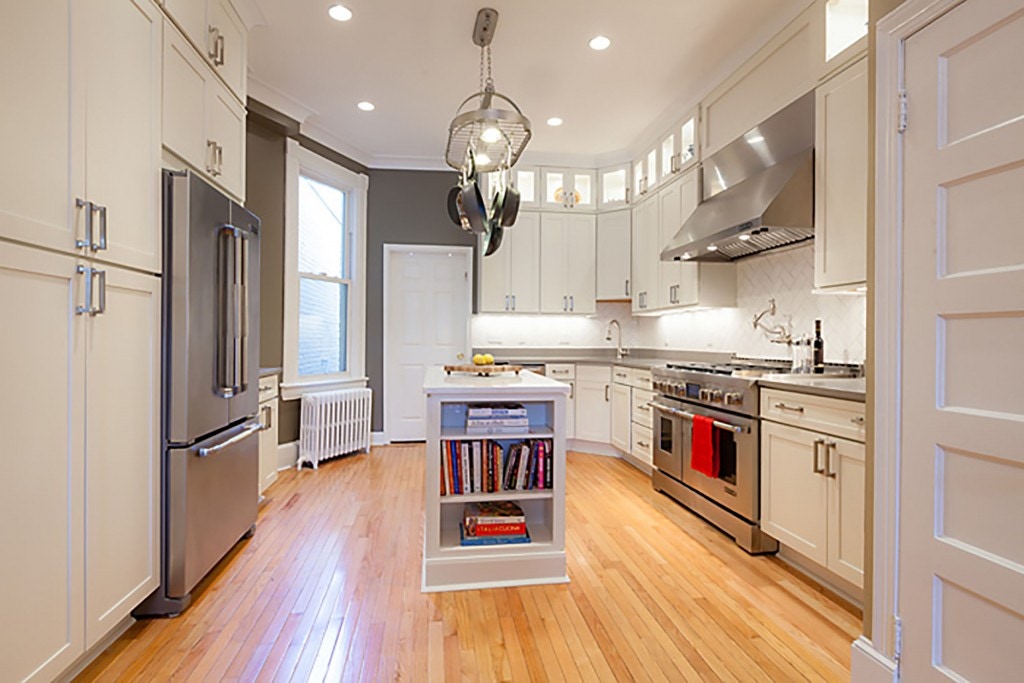 long view of remodeled kitchen in Washington DC townhouse, with refinished oak floors, hot water radiator, double refrigerators, white cabinets, bookshelf on end of center island and professional range and hood long view of remodeled kitchen in Washington DC townhouse, with refinished oak floors, hot water radiator, double refrigerators, white cabinets, bookshelf on end of center island and professional range and hood