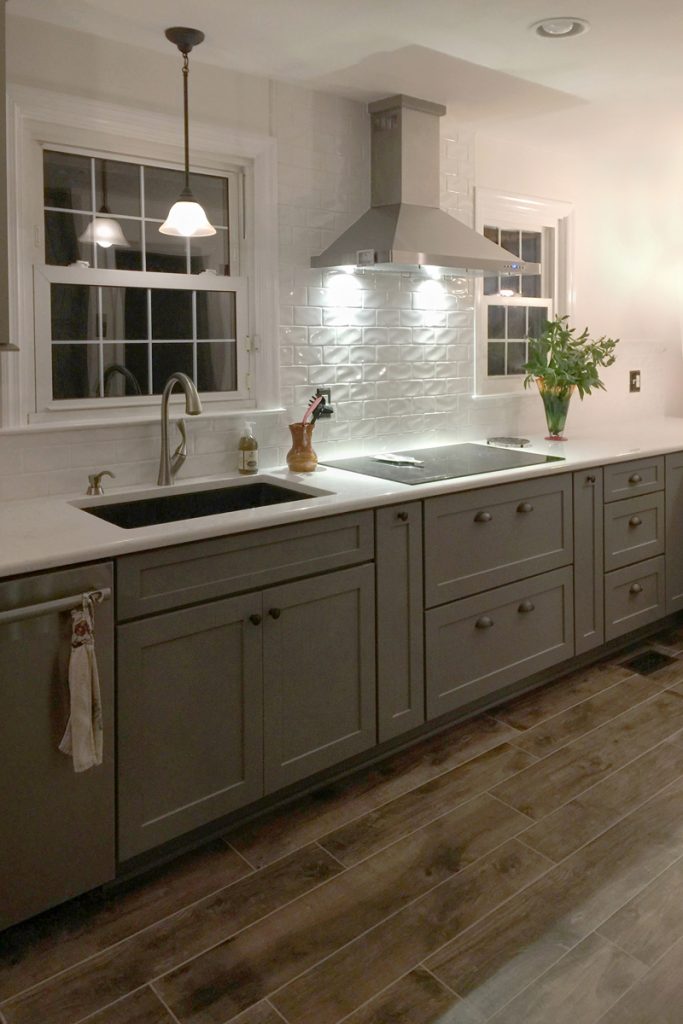 Cooktop with stainless hood, white backsplash and gray storage cabinets below Cooktop with stainless hood, white backsplash and gray storage cabinets below