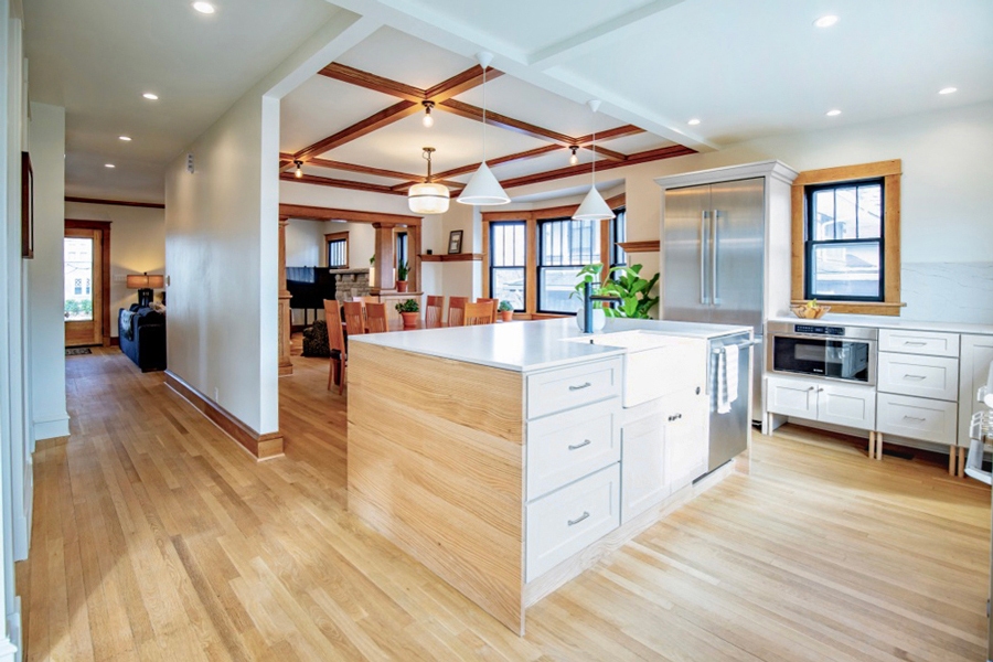 Open concept white shaker kitchen with large island and blonde wood flooring Open concept white shaker kitchen with large island and blonde wood flooring