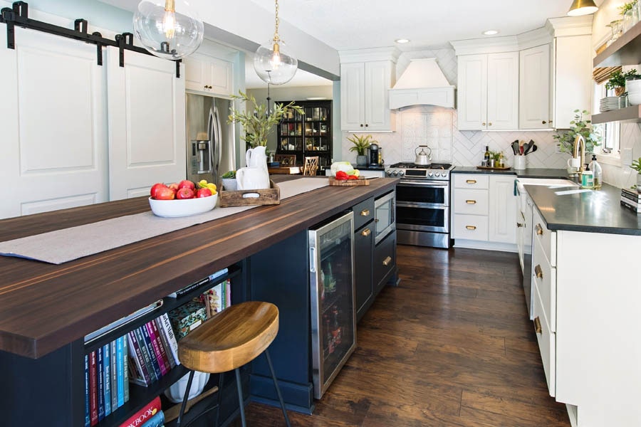 A black island with butcher block counter tops and a built in microwave, bookshelf, and cooler. A black island with butcher block counter tops and a built in microwave, bookshelf, and cooler.