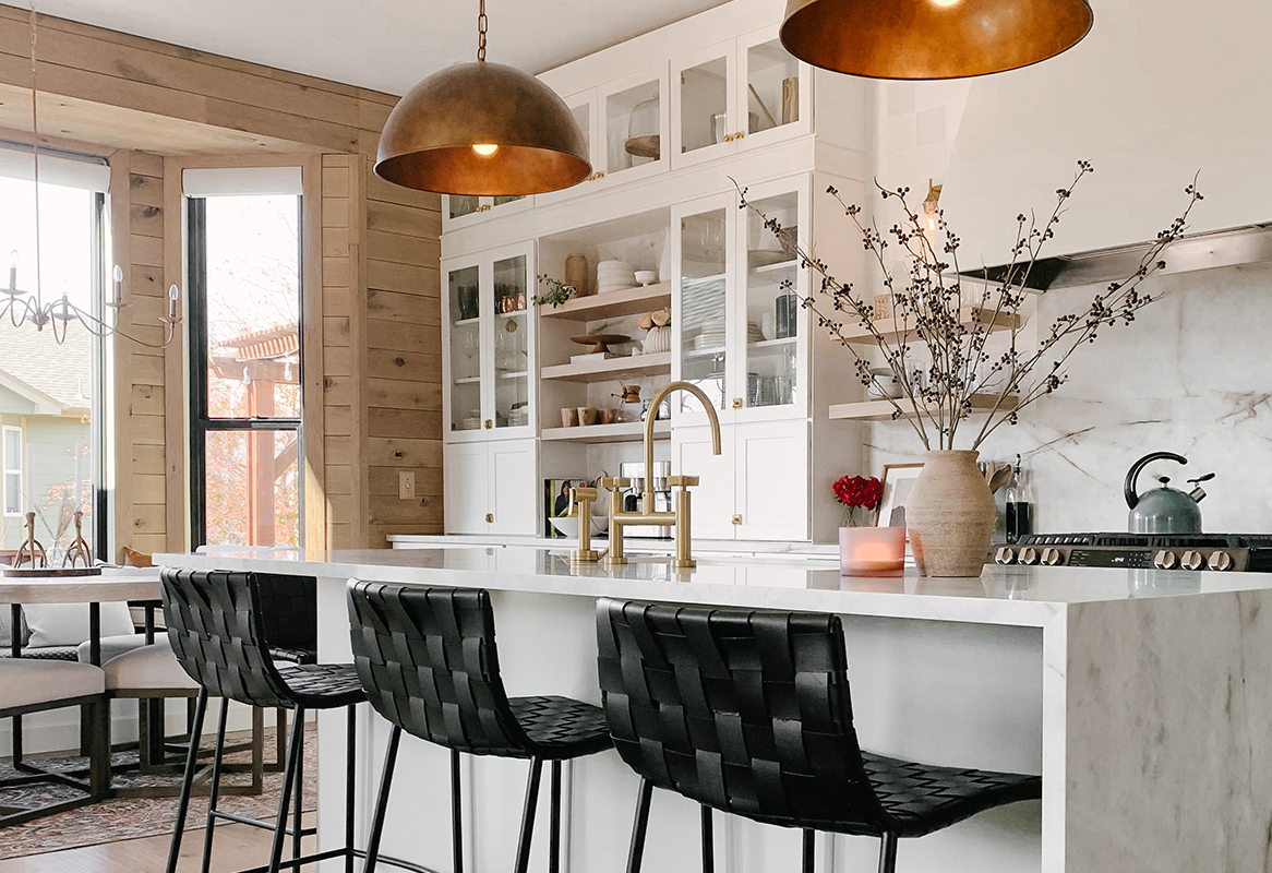 CliqStudios project: Open concept white shaker kitchen with half-waterfall marble island top, a large custom cream hood, glass buffet cabinets, copper pendants and black accents CliqStudios project: Open concept white shaker kitchen with half-waterfall marble island top, a large custom cream hood, glass buffet cabinets, copper pendants and black accents
