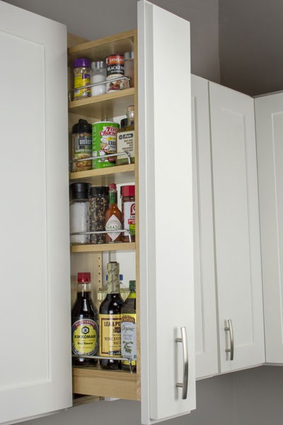 Pull-out storage cabinet with three shelves storing spices and other small assorted jars. Pull-out storage cabinet with three shelves storing spices and other small assorted jars.