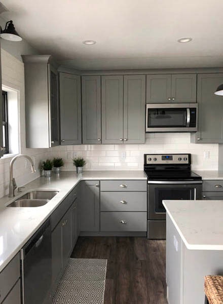 Gray Shaker cabinets surrounded by white countertops and backsplash with undermount sink and stainless appliances. Gray Shaker cabinets surrounded by white countertops and backsplash with undermount sink and stainless appliances.