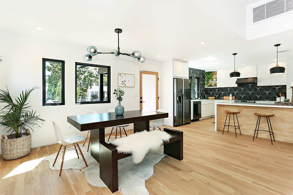 White slab kitchen cabinets with natural wood finish peninsula and black retro backsplash White slab kitchen cabinets with natural wood finish peninsula and black retro backsplash