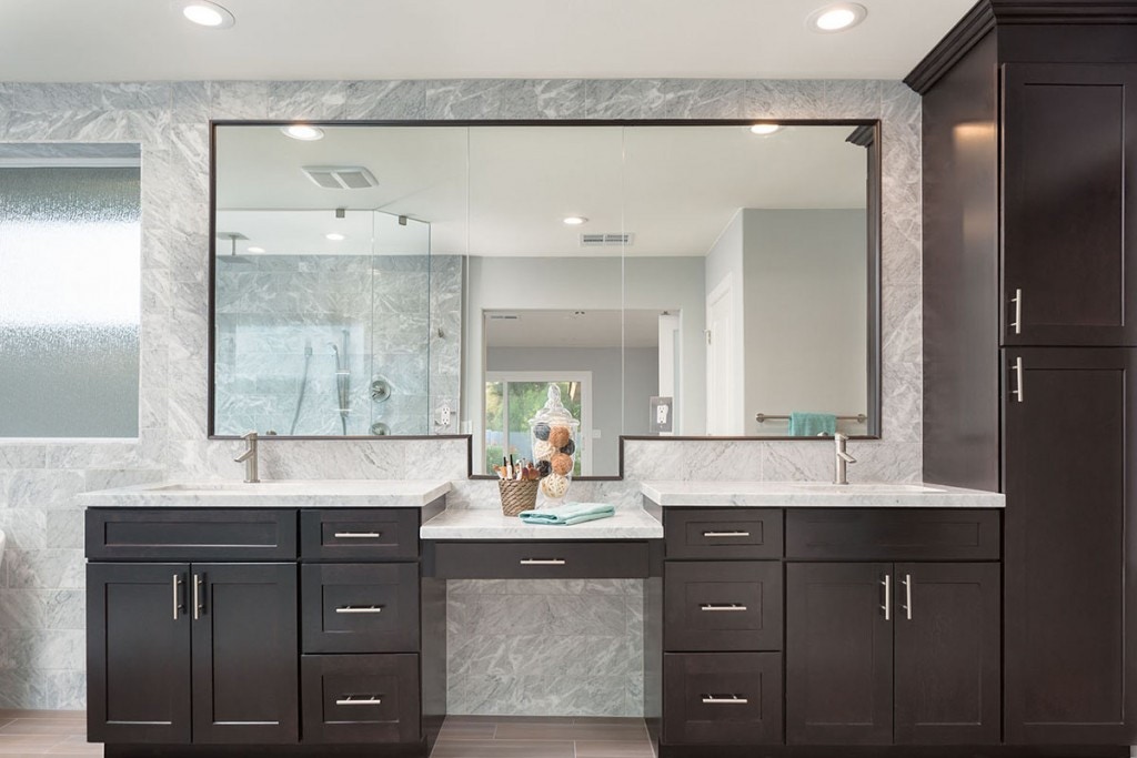Dark brown shaker vanity cabinets Dark espresso shaker vanity cabinets in master bath with two sinks separated by a makeup desk and tall linen closet on the right side