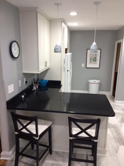 peninsula kitchen design has black granite countertops, black transitional bar stools, white shaker cabinets and glass pendant lights peninsula kitchen design has black granite countertops, black transitional bar stools, white shaker cabinets and glass pendant lights