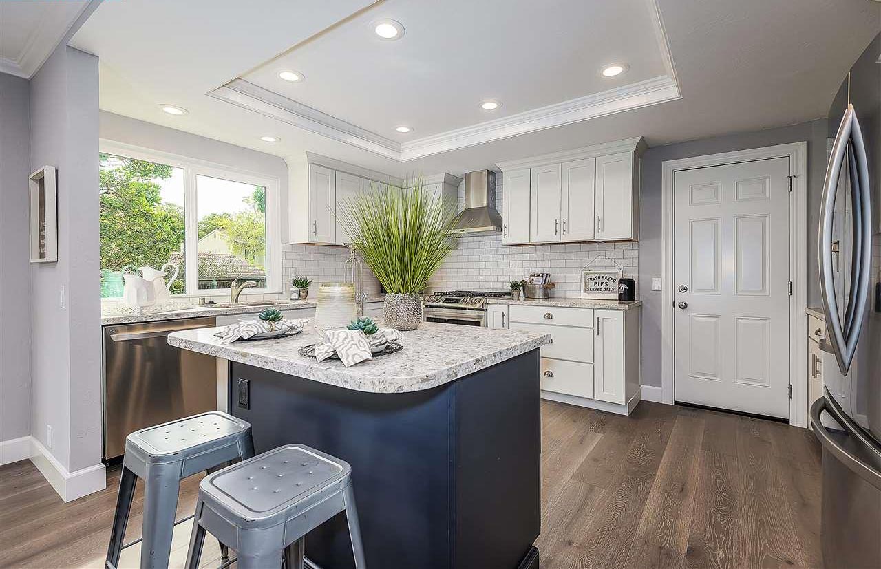 White shaker-style kitchen cabinets with blue shaker island and white quartz countertops White shaker-style kitchen cabinets with blue shaker island and white quartz countertops