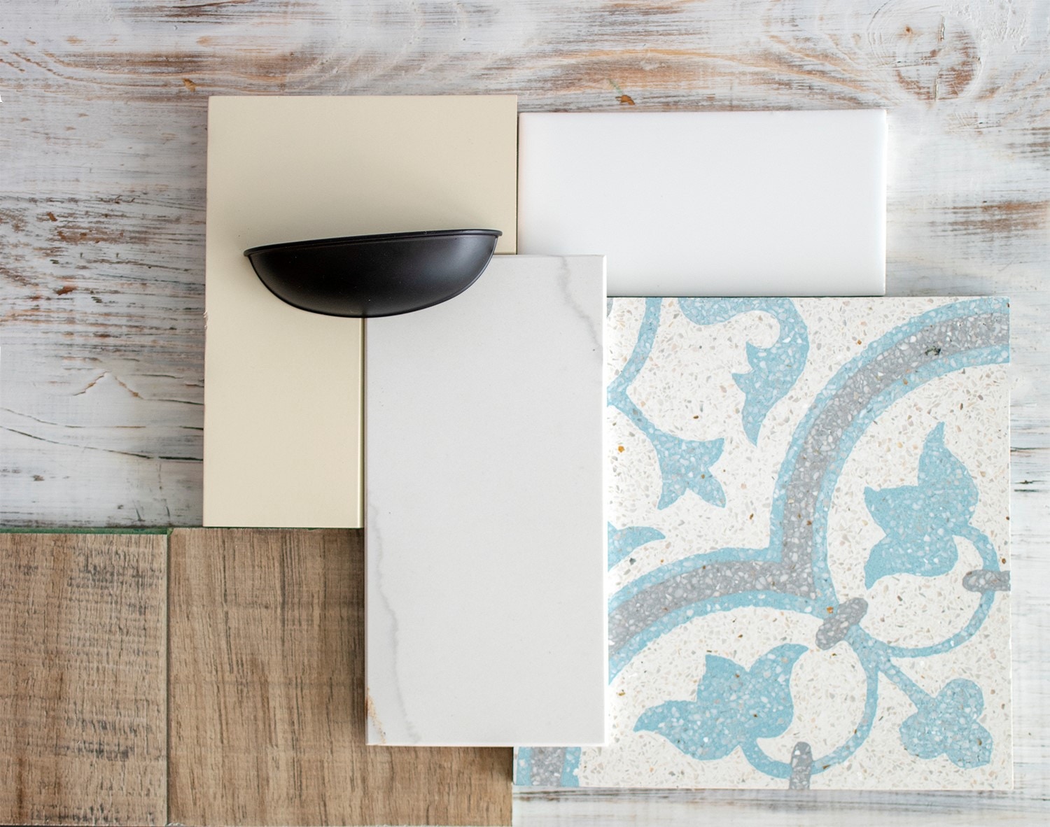Design mood board featuring white tile, black cup pull, white cabinet sample and wood background Design mood board featuring white tile, black cup pull, white cabinet sample and wood background