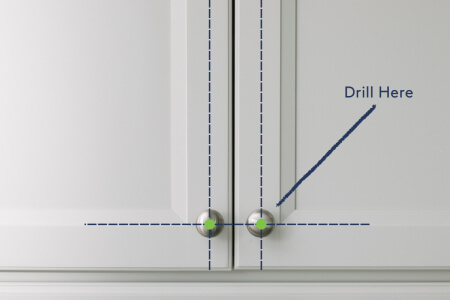 White shaker kitchen cabinet with a diagram of where to drill for cabinet hardware.