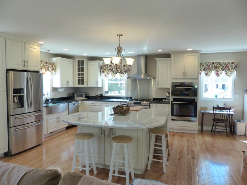 open kitchen viewed from family room has large island with seating on two sides, white traditional cabinets, oversized stainless apron front sink and ornate chandelier over island open kitchen viewed from family room has large island with seating on two sides, white traditional cabinets, oversized stainless apron front sink and ornate chandelier over island