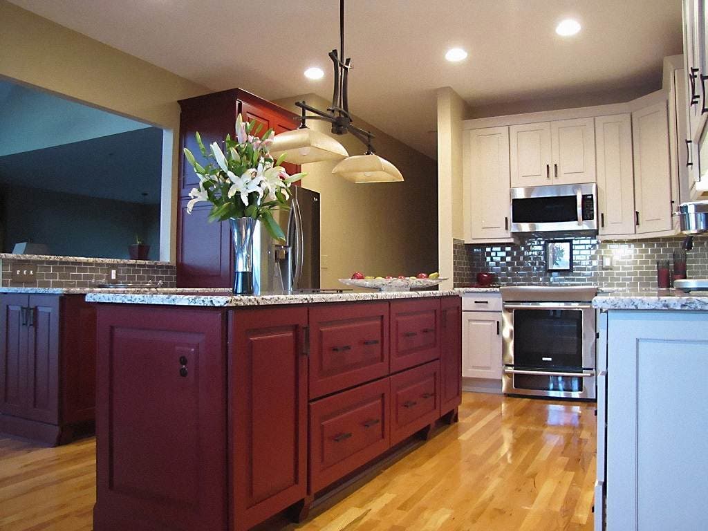 Two-tone kitchen with red center island and white perimeter cabinets in a raised panel cabinet style with gray granite countertops and hardwood flooring Two-tone kitchen with red center island and white perimeter cabinets in a raised panel cabinet style with gray granite countertops and hardwood flooring