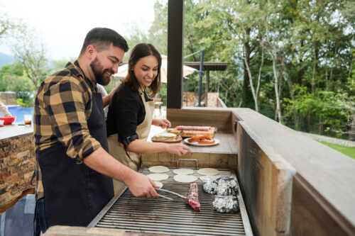 Couple grilling outside in their outdoor kitchen.