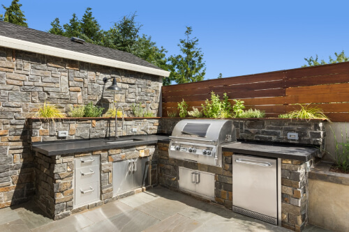 Outdoor kitchen with stainless steel outdoor cabinets and stone surrounding