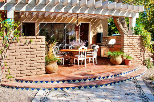 Outdoor kitchen with wood surround and stainless steel grill.