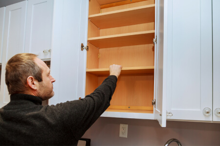Man re-assembling kitchen cabinets by placing shelves inside