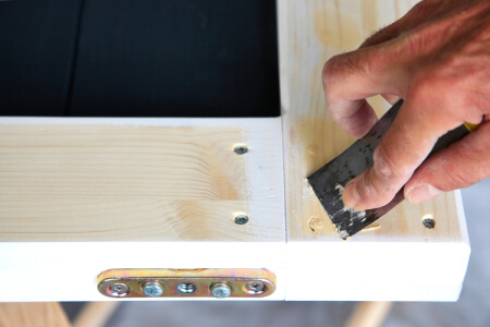 Kitchen cabinet door being repaired with wood putty