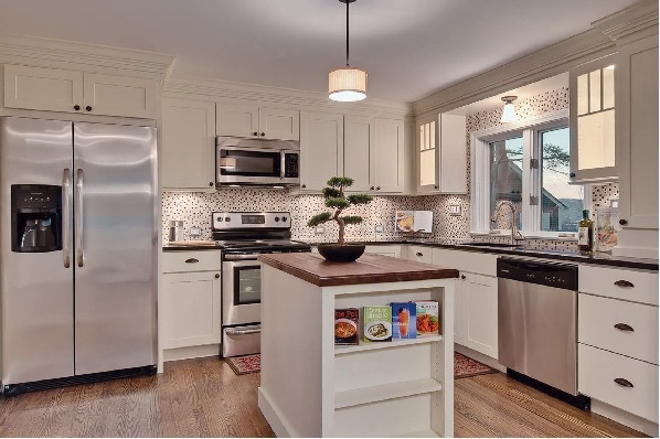 White shaker cabinets in kitchen have stacked crown molding to meet ceiling White shaker cabinets in kitchen have stacked crown molding to meet ceiling
