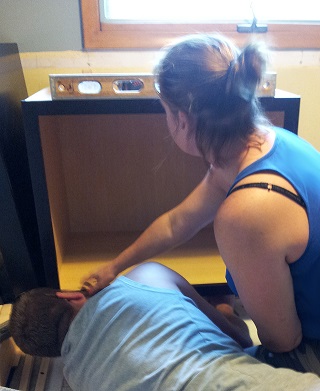 Designer Tessa and husband Jake work together, leveling a base cabinet in their kitchen Designer Tessa and husband Jake work together, leveling a base cabinet in their kitchen