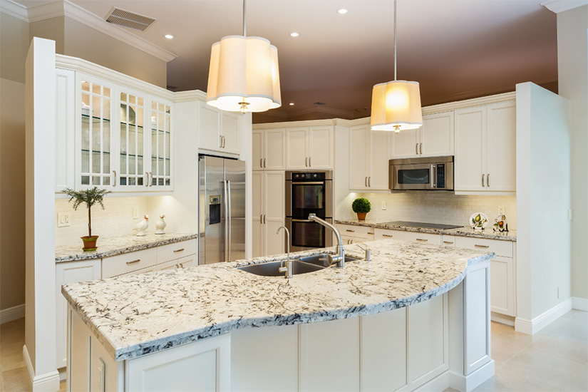 White shaker kitchen cabinets Traditional large white shaker kitchen design with baseboard and crown molding, mullion glass doors, stainless steel appliances, and white and brown speckled granite countertops.