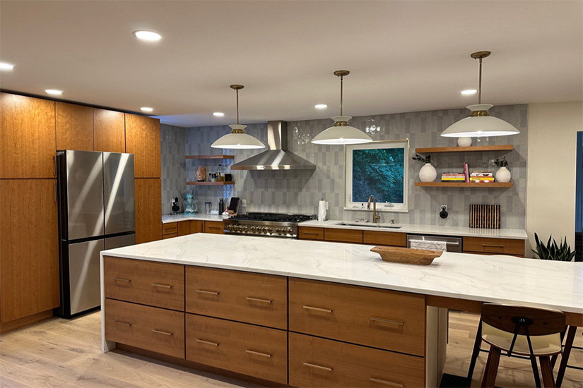 Wynn Cherry Sandalwood kitchen cabinets Large Modern slab door kitchen and long island with white quartz countertops with a waterfall edge.